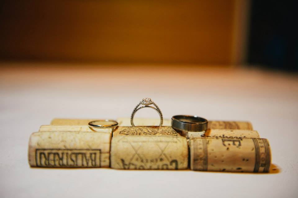A close up of wedding rings pinched between wine corks